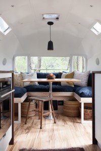 The dining area features a custom table made from salvaged oak boards and a marine pedestal leg, while the flooring is maple. Photograph by Kate Oliver