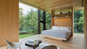 Privacy in the master bedroom is provided by sliding solid-oak panels on the left and a custom white oak room divider that acts as a headboard on one side and a bookcase on the other.