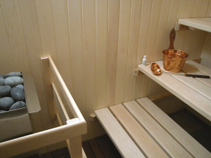A small sauna with white aspen tongue-and-groove paneling and matching basswood benches in a three-tier bench layout. Superior Sauna & Steam