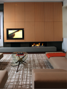 In a New York City loft by architect Jae Chang a wall of golden rift-sawn maple paneling floats above a gas fireplace on an elongated hearth made of pietra serena, a gray Italian sandstone. Photograph by Rob Kassabian