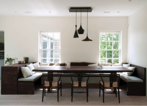 In the dining area of a Remsenburg, NY, weekend house by D'Apostrophe Design, Tom Dixon pendant lamps and Hans Wegner Wishbone chairs join a custom-made American walnut table and banquette.