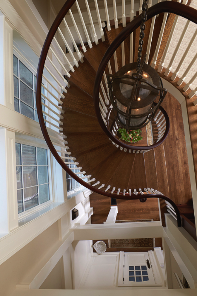 As the stairs spiral upward, they encircle a chandelier hanging from the ceiling on the top floor.