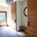 A pair of closets with custom sliding doors in American black walnut in the entry hall of an Upstate New York weekend house by architect Nina Gotlieb of Actual Size Projects