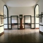 The Shakers loved symmetry. Separate dining-room doorways for men and women create a mirror image in the Center Family Dwelling hallway at the Shaker Village of Pleasant Hill in Kentucky. Painted maple chairs hang from wall pegs. The floor is quarter-sawn oak, the trim painted poplar. 