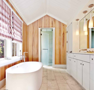 Poplar siding on the master bathroom walls provides a warm contrast with the white tub and the stone-tile floor.
