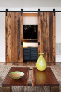 In a Richmond, VA, residence by Fraser Design, the living-room media center is housed behind rustic barn doors made of reclaimed red and white oak from 19th-century agrarian buildings. Photograph by Ansel Olson