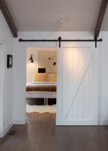 Tineke Triggs of Artistic Designs for Living hung a simple painted-poplar barn door between the living area and master bedroom in a Mill Valley, CA, farmhouse. 
