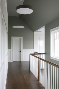 In the upstairs hallway, designer Laura Bohn juxtaposes medium-gray walls and white-painted poplar paneling and molding with medium-dark walnut floors and bannisters. Photograph by David Gilbert